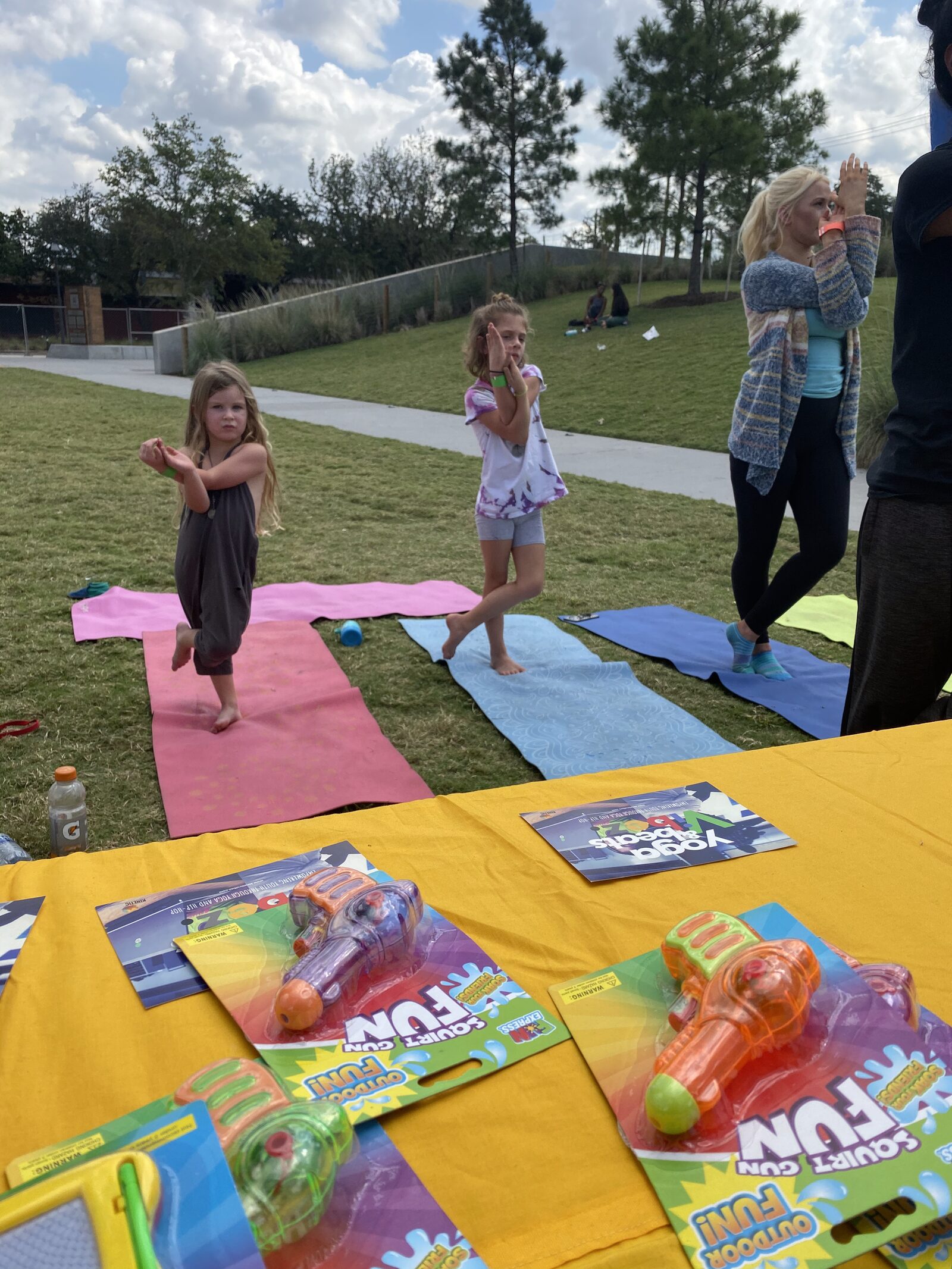 Children and instructor doing yoga balance poses on colorful mats outdoors during a Creative Wellness Through Hip-Hop session